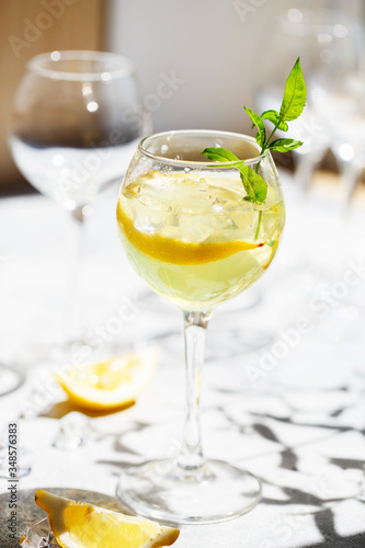 Lemonade or mojito cocktail with lemon and mint, cold refreshing drink or beverage with ice. Homemade limoncello in a glass on a thin leg. A Margarita Cocktail with a lemon slice
