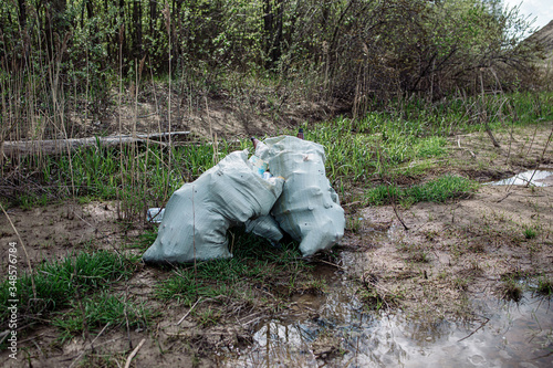 A pile of garbage near the river. A conceptual photograph of the problem of pollution of the sea and nature, which affects marine life, like turtles. Plastic needs up to 450 years to decompose