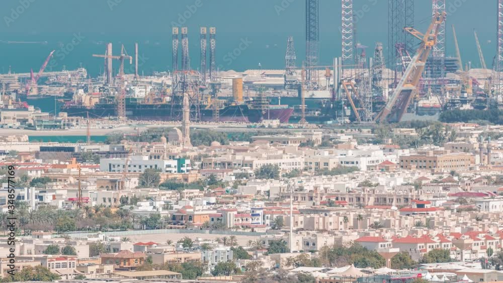 Aerial evening view from Downtown of Dubai timelapse with skyscrapers, houses and port Rashid on a background, ships docking at sea port, UAE Aerial evening view from Downtown of Dubai timelapse with skyscrapers, houses and port Rashid on a background, ships docking at sea port, UAE