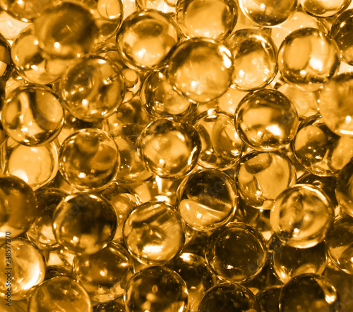 Fish oil pills. Transparent round capsules of vitamin as an abstract background. Small gold-yellow balls close-up. Concept of treatment and prevention of health. 