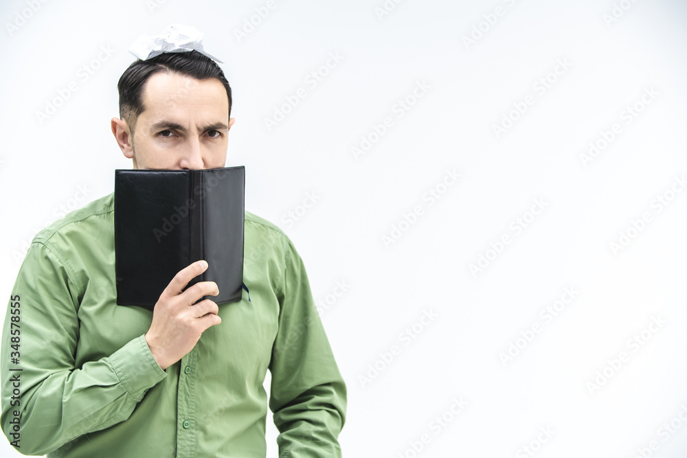 Mature businessman peeking over black notebook with suspicious, distrustful face expression over white background with copyspace for text or product.