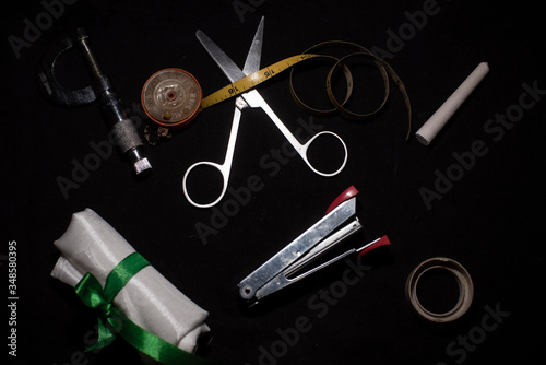 A collection of scissor, slide calipers, measuring tape, stapler and other office accessories in a dark copy space background. Product photography.