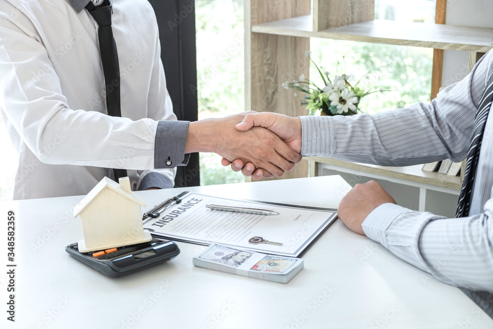 Fototapeta premium Real estate agent are shaking hands after good deal and giving house, keys to customer after signing contract to buy house with approved property application form