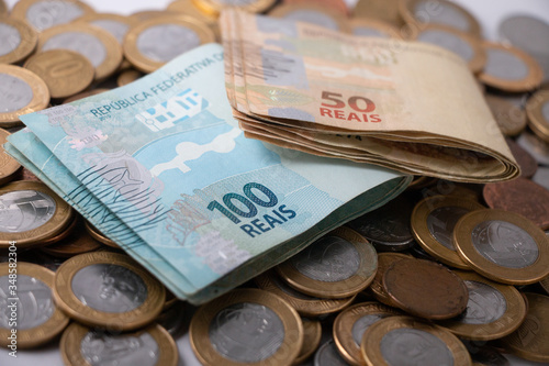 Dinheiro celulose e moedas brasileiras , notas de cem e cinquenta reais em fundo branco photo