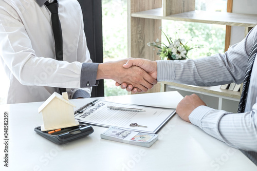 Real estate agent are shaking hands after good deal and giving house, keys to customer after signing contract to buy house with approved property application form