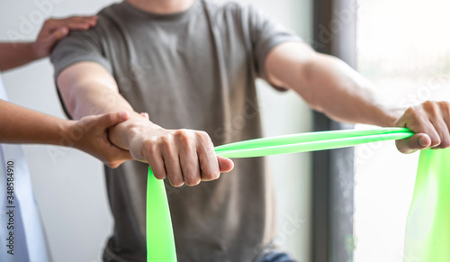 Doctor or Physiotherapist working examining treating injured arm of athlete male patient, stretching and exercise, Doing the Rehabilitation therapy pain in clinic