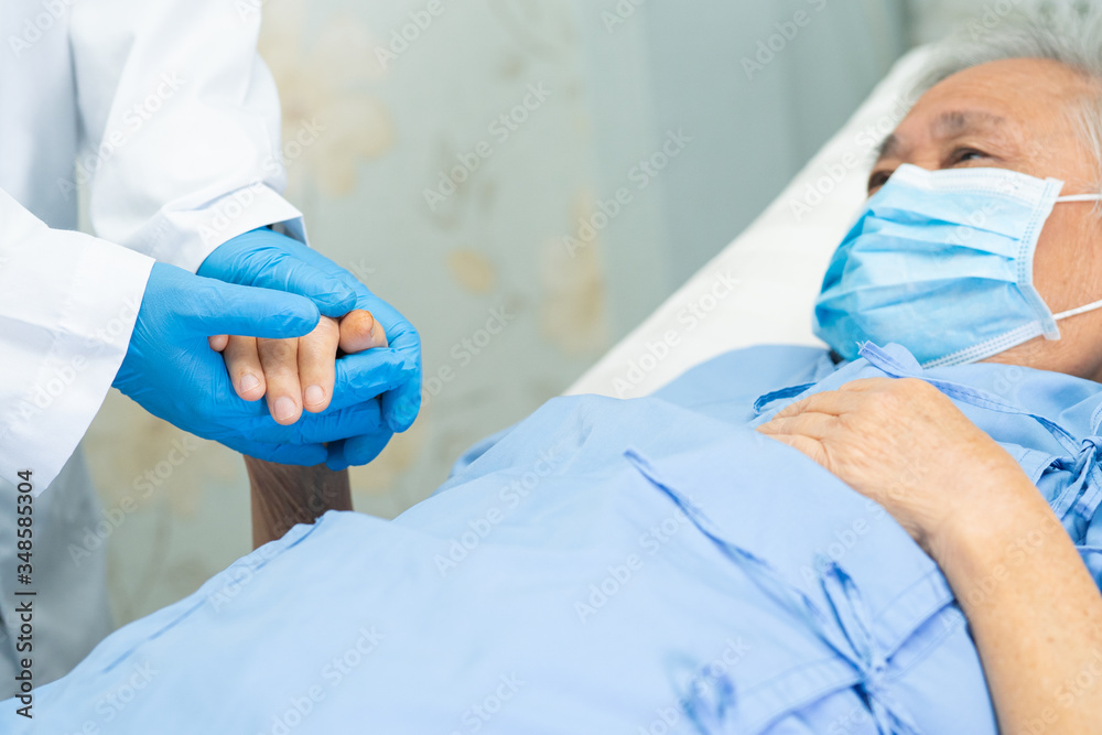 Doctor holding hand Asian senior or elderly old lady woman patient wearing a face mask in hospital for protect infection and kill Novel Coronavirus Covid-19 virus. Doctor holding hand Asian senior or elderly old lady woman patient wearing a face mask in hospital for protect infection and kill Novel Coronavirus Covid-19 virus.