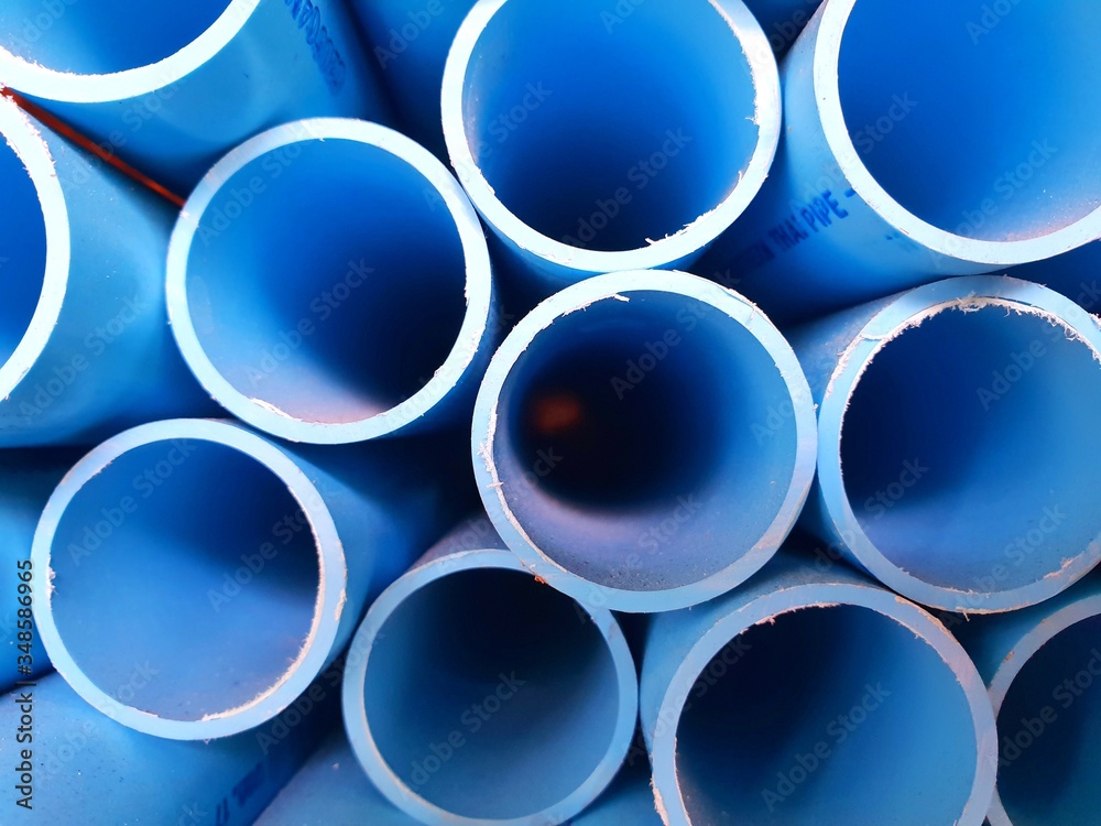 stack of long uncut blue pvc pipes on a shelf in a warehouse 