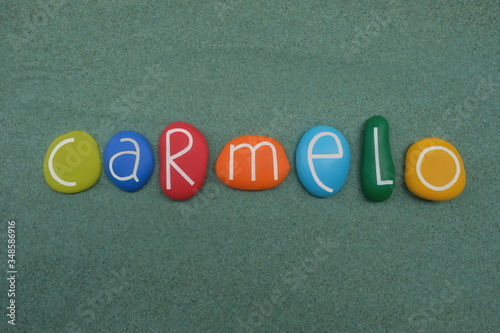 Carmelo, male given name composed with multi colored stone letters over green sand