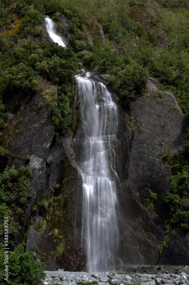 Waterfall next to Franz Josef Glacier in West Coast of South Island, New Zealand Waterfall next to Franz Josef Glacier in West Coast of South Island, New Zealand