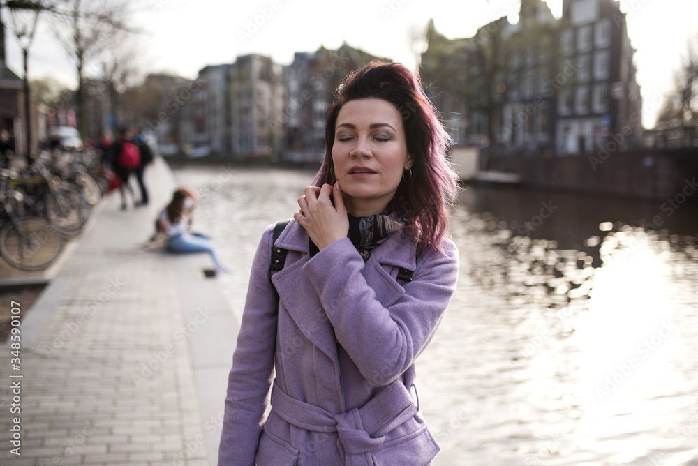 Girl in the coat and backpack enjoying Amsterdam city, Netherlands