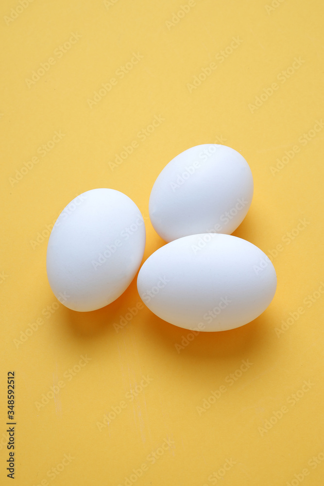 Eggs,Three White egg on the yellow background in center,Copy space for the ads Eggs,Three White egg on the yellow background in center,Copy space for the ads