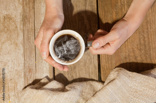 the girl's hands hold a Cup of hot coffee