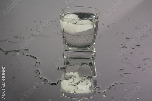 Bartender pouring up frozen vodka from a bottle into two shots glasses with ice cubes against black background. Barman pour of clear transparent alcohol drink rum tequila in shot-glass