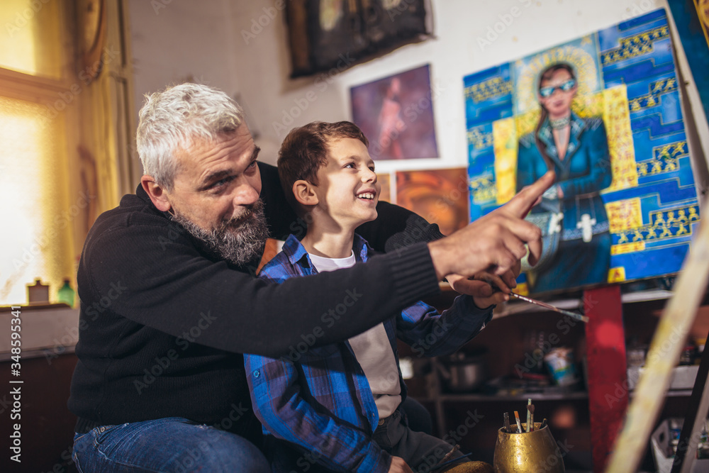 Father and son working and painting together in art studio Father and son working and painting together in art studio