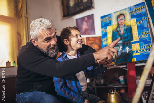 Father and son working and painting together in art studio © Mediteraneo