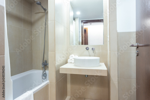 Modern bathroom with bathtub  mirror and washbasin. European hotel design.