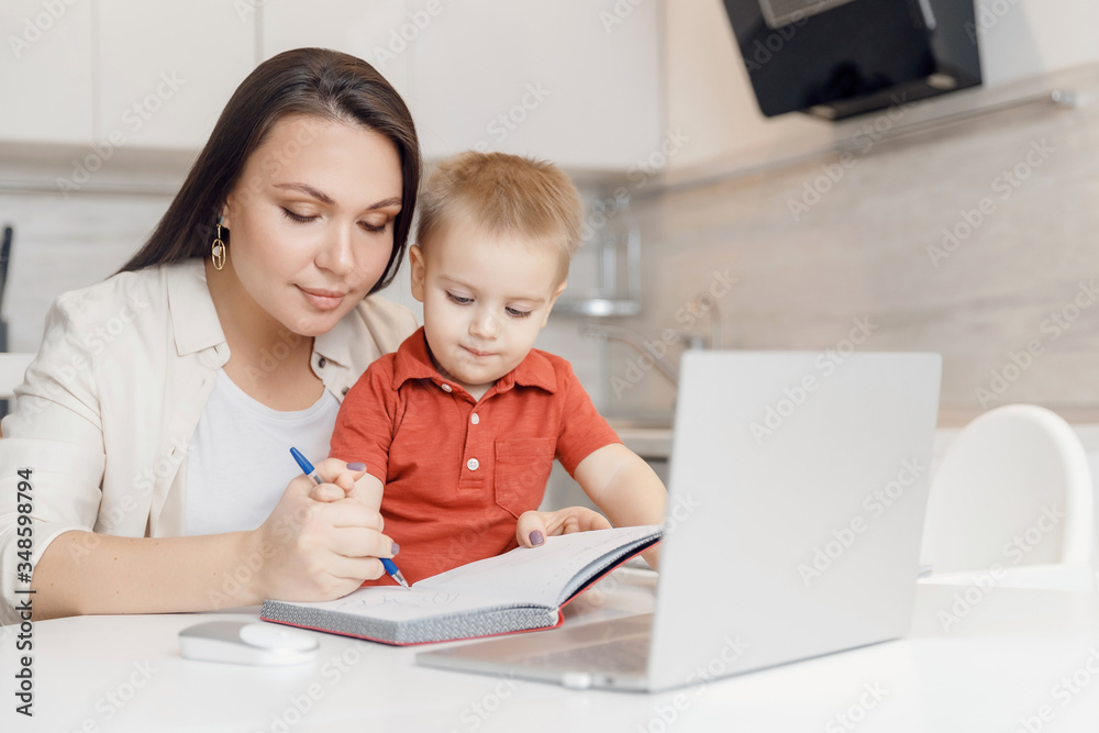 Beautiful woman helps son learn how to write alphabet letters. Online learning concept Beautiful woman helps son learn how to write alphabet letters. Online learning concept