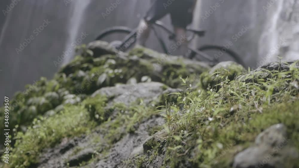 Cyclist with bike enjoying view of mountain waterfall Cyclist with bike enjoying view of mountain waterfall