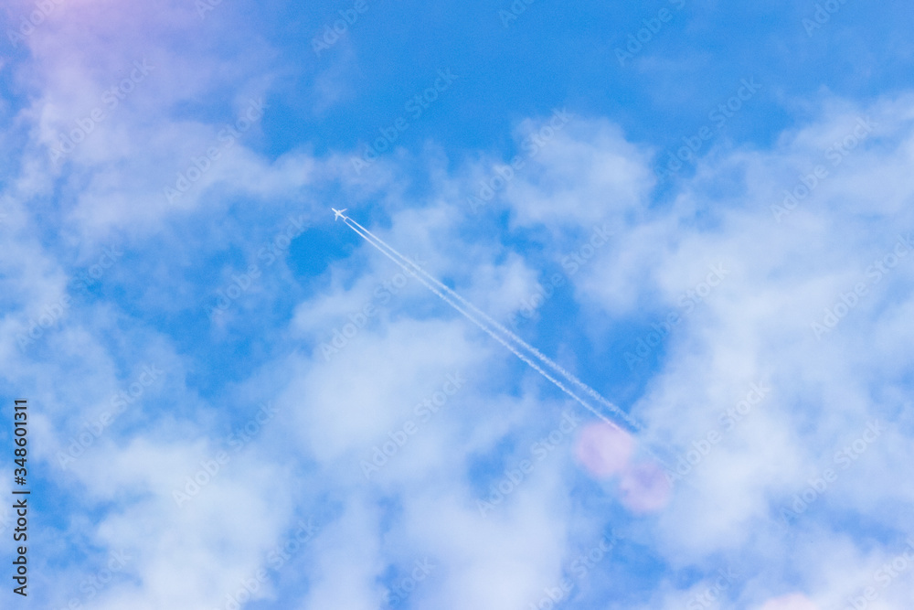 the plane flies among the clouds against the blue sky, leaving a trail behind it. The concept of ending the coronavirus pandemic and increasing air travel. the plane flies among the clouds against the blue sky, leaving a trail behind it. The concept of ending the coronavirus pandemic and increasing air travel.