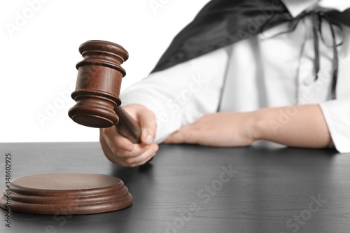 Little judge sitting at table against white background, closeup photo