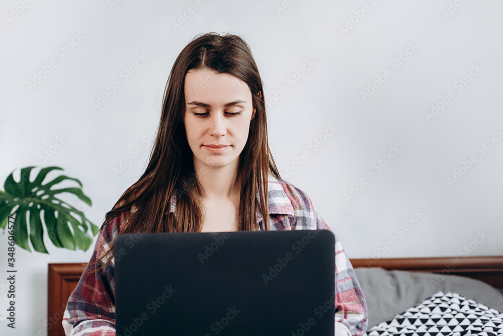 Front view of young pretty woman freelancer working on freelance from home typing email on laptop, focused girl using computer for study online at home sitting on cozy bed at home. Front view of young pretty woman freelancer working on freelance from home typing email on laptop, focused girl using computer for study online at home sitting on cozy bed at home.