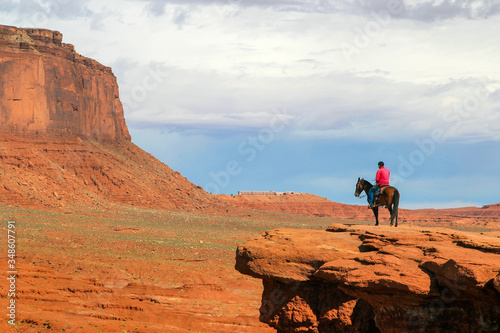 Uomo navajo a cavallo nella Monument Valley photo
