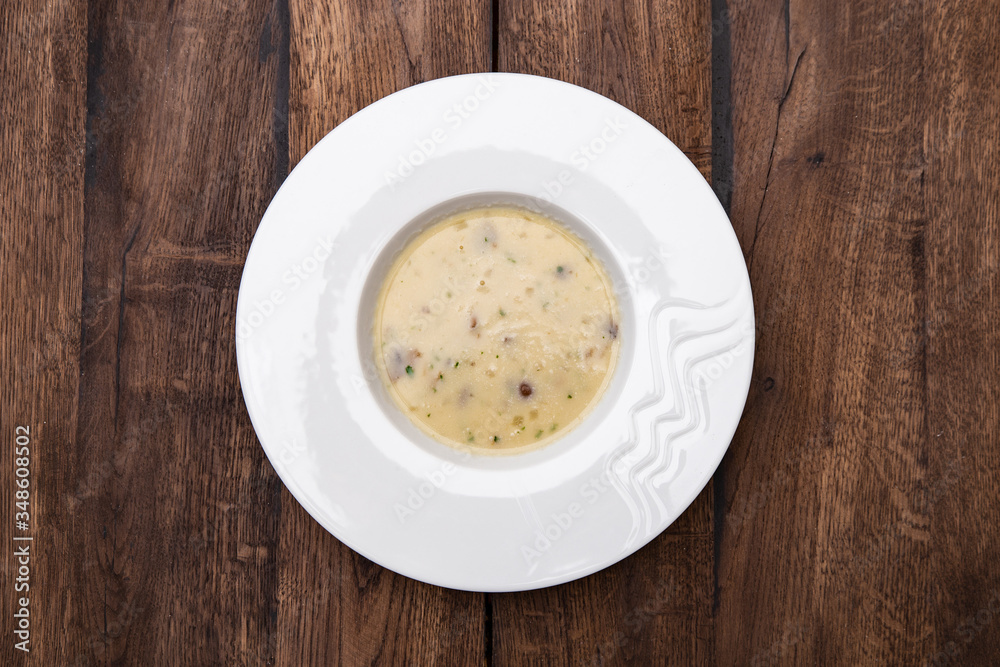 Cream soup with mushrooms and on wooden table. A plate of Mushroom Cream-soup. Top view. Cream soup with mushrooms and on wooden table. A plate of Mushroom Cream-soup. Top view.
