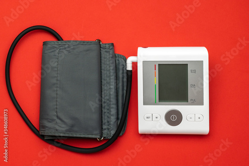 Blood pressure check. Health monitor for check doctor blood pressure isolated on red background. Patient test hypertension from medical sphygmomanometer. Flat lay, top view, copy space.