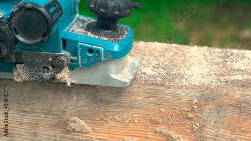 Fotografie Worker planing electric planer piece of wood.