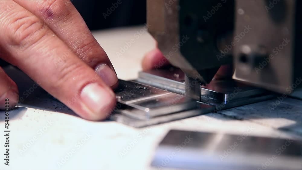 Man sawing piece of steel in an electric saw Man sawing piece of steel in an electric saw