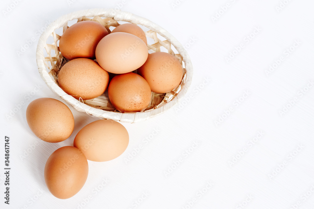 Brown chicken eggs in a straw basket on white wooden background. Top view with copy space. Brown chicken eggs in a straw basket on white wooden background. Top view with copy space.