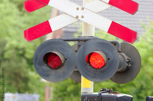 Fotografie Red stop signal at a level crossing with trees in the background