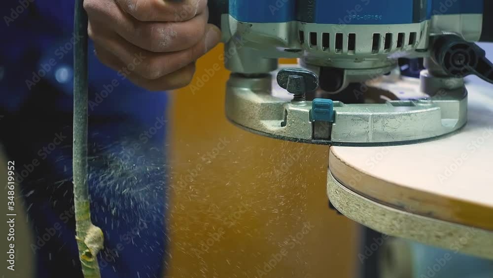 a man processes a fiberboard with a milling machine in slow motion