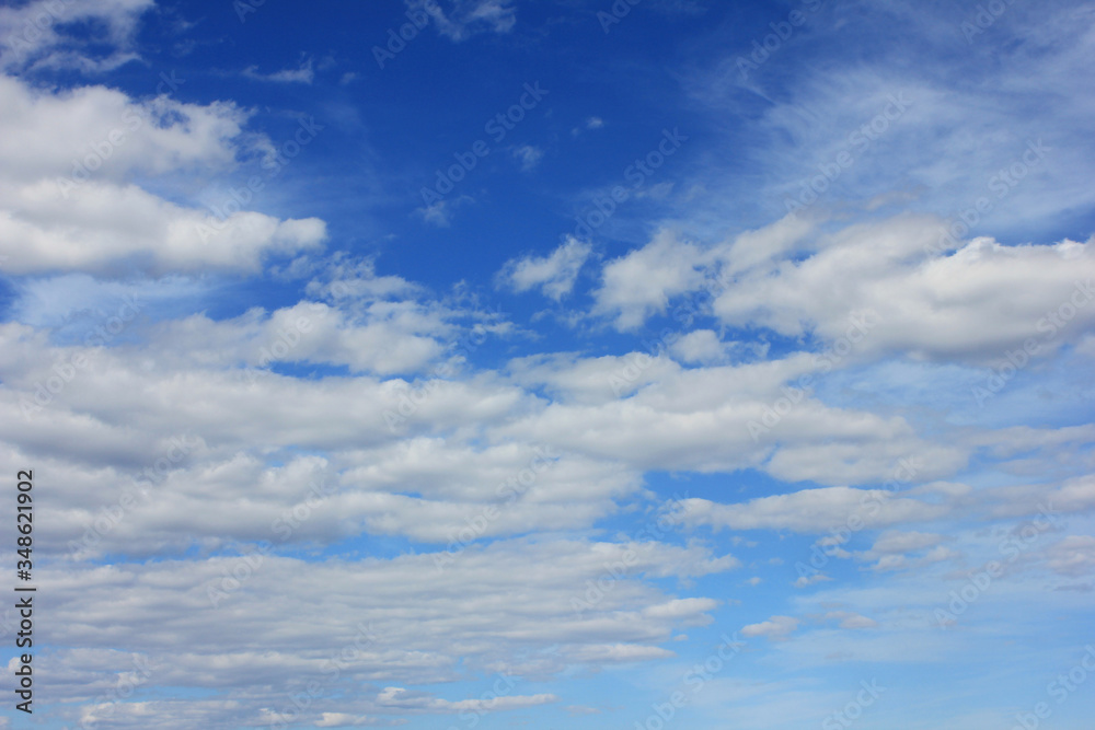 Cloudy blue sky nature background. White puffy clouds on bright blue sky texture, cloudscape natural wallpaper. Bright blue sky with clouds on sunny day