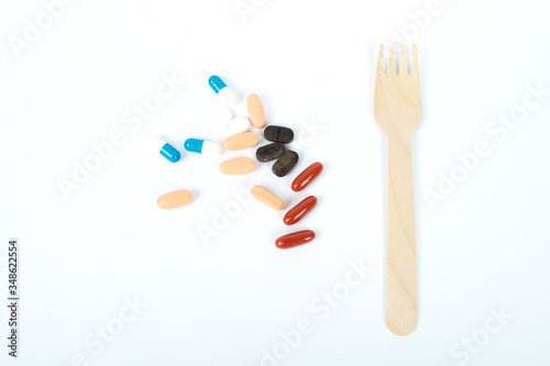 Handful of pills and an eco-friendly disposable fork. Food for illness. Medicine concept. Epidemic coronavirus 2019-nCoV. Flat lay.