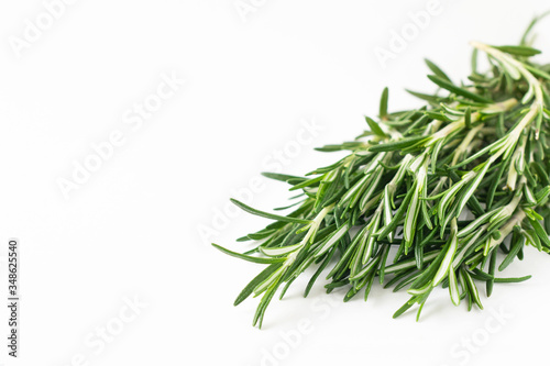 Fresh bouquet of rosemary leaves in a white ceramic bowl on white light background. Selective focus.