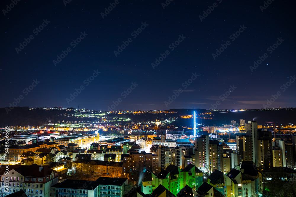 Obraz premium Germany, Magical starry night sky over modern buildings of swabian city esslingen am neckar, aerial view above the illuminated houses and roofs by night