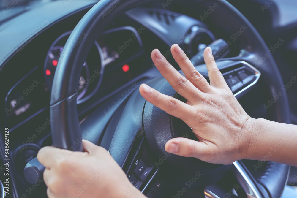 person pushing horn while driving sitting of a steering wheel press car
