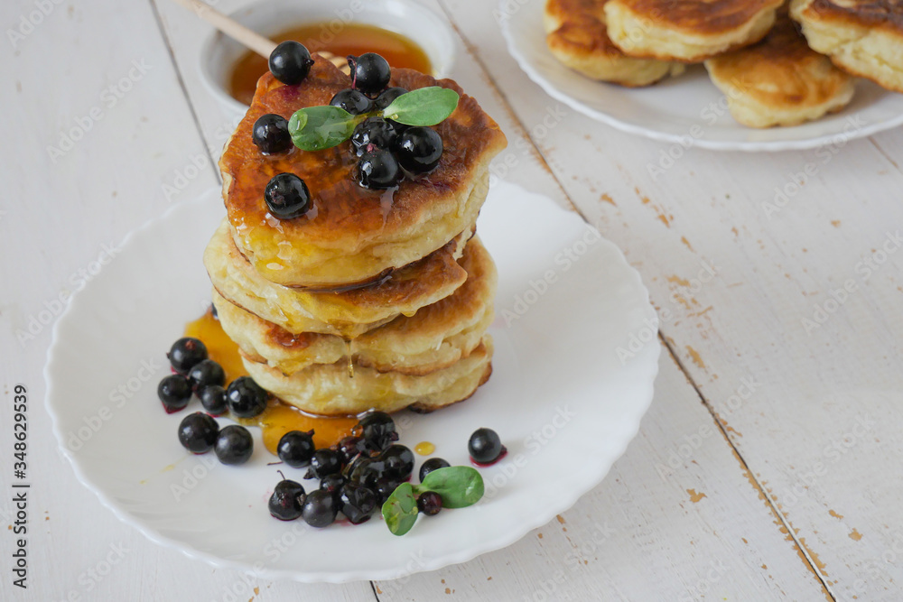 Fritters. Traditional pancakes in a stack on a white plate. White background. Berries and honey. copyspace