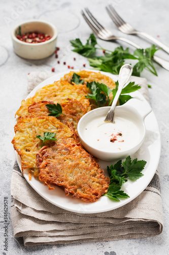 Draniki - potatof ritters, vegetarian potato pancakes, served with fresh herbs and garlic yogurt sauce, top view.