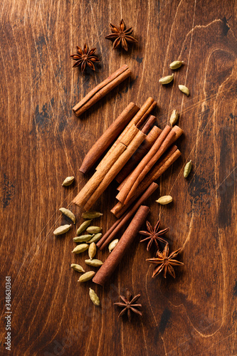Fototapeta Naklejka Na Ścianę i Meble -  Assorted natural cinnamon, cardamoms and anise stars baking ingredients on a rustic brown background.
