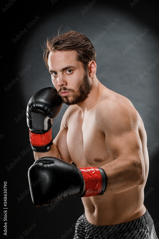 A man in Boxing gloves. A man Boxing on a black background. The concept of a healthy lifestyle