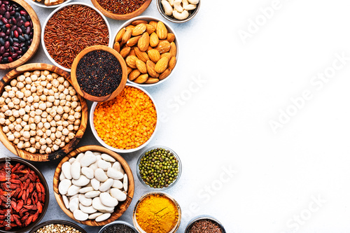 Various superfoods, legumes, cereals, nuts, seeds in bowls on white background. Superfood as chia, spirulina, beans, goji berries, quinoa, turmeric, mung bean, buckwheat, lentils, flax seed, wild rice