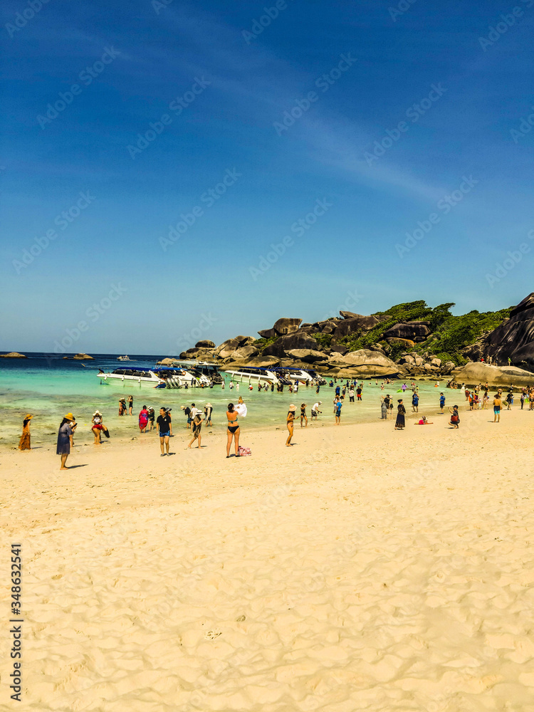 People relax and sunbathe on a sandy beach off the coast of the Similan Islands on a summer sunny day. People relax and sunbathe on a sandy beach off the coast of the Similan Islands on a summer sunny day.