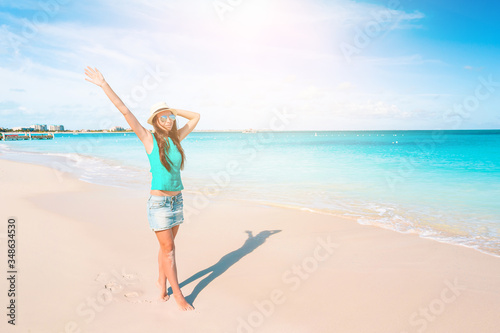 Young beautiful woman having fun on tropical seashore. Happy girl background the blue sky and turquoise water in the sea on caribbean island