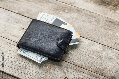 Black wallet with banknotes, electronic cards and bitcoins on a wooden background. Symbol of prosperity and prosperity.