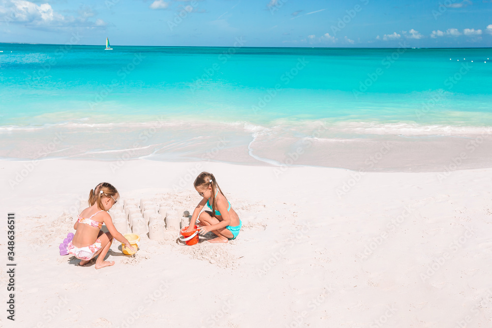 Two kids making sand castle and having fun at tropical beach