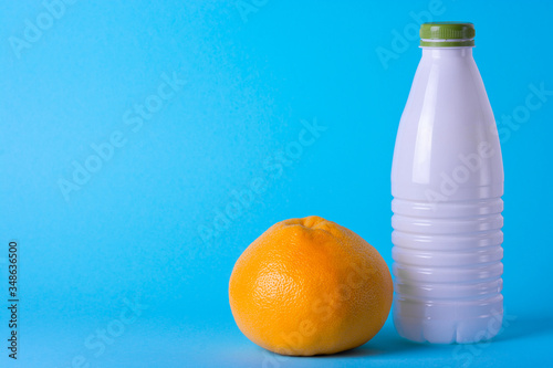 Plastic white bottle on a light blue background with grapefruit photo