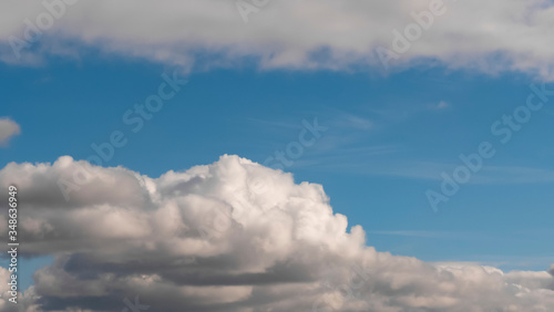 Sky with clouds. Lush  large Cumulus clouds in a clear blue sky illuminated by the rays of the sun on a Sunny day. Realistic sky background. Template. 
